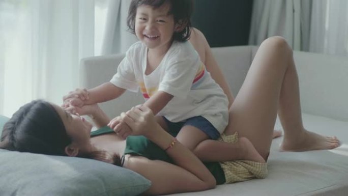 在客厅里，年轻的亚洲母子牵着手在客厅里玩耍。