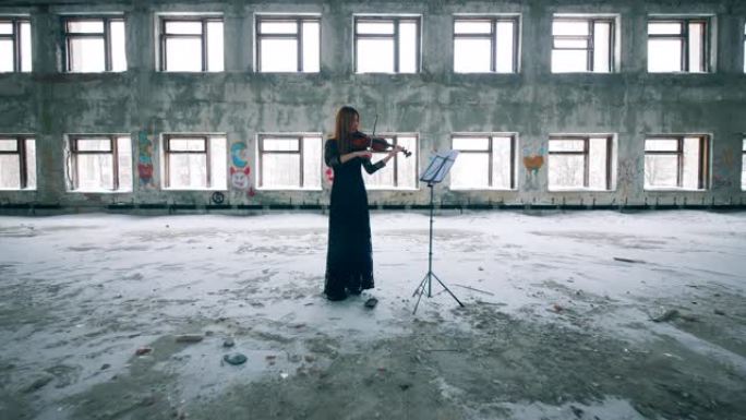一名妇女拉小提琴的废弃建筑