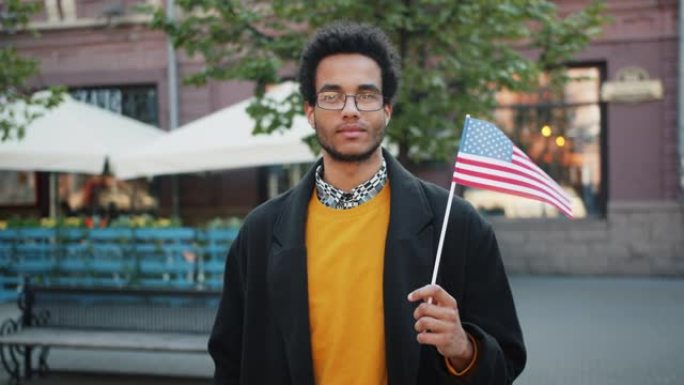 吸引人的非洲裔美国学生举着美国国旗站在户外的肖像