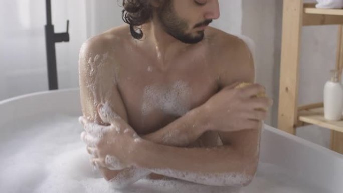 肌肉男在洗澡时用海绵清洁自己