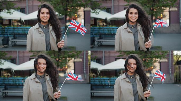 在大风天，快乐的女孩站在户外，带着英国国旗微笑的肖像