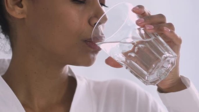 渴了的非洲女人早上拿着杯子喝水，特写镜头