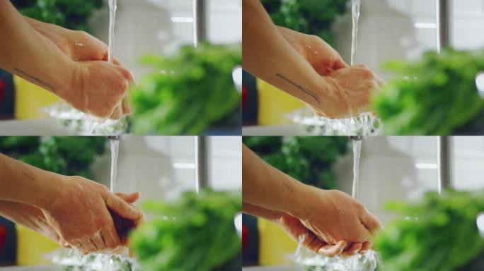 慢动作特写镜头，一个纹身的时尚男人用自来水洗手。正宗时尚厨房水槽配健康蔬菜。家里自然清洁。