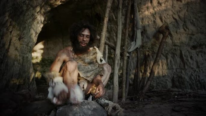 穿着动物皮的原始穴居人拿着骨头，用它击中岩石。尼安德特人在洞穴入口附近鬼混，也许是偶然创造了第一个原