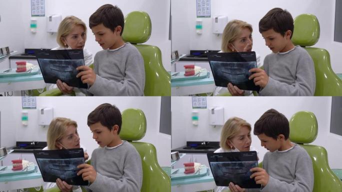 可爱的牙齿科医生向年轻患者解释一些东西，同时向他展示他牙齿的x射线