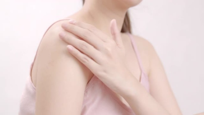 亚洲成年女性用手在肩膀上涂抹保湿霜。身体护理概念。