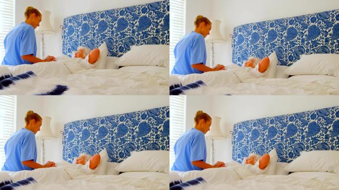 在舒适的家庭4k中，年轻的高加索女医生在床上握着高级女性的手的侧视图