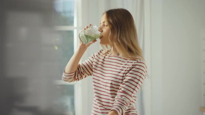 美丽的年轻女性喝一杯健康的绿色冰沙。正宗的时尚厨房配健康蔬菜。有机农业生产的天然清洁产品用于制作奶油
