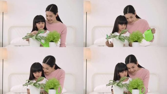 年轻的亚洲母亲教她的小女儿在卧室种树。