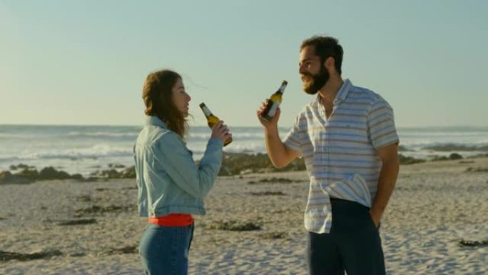 年轻夫妇在阳光明媚的日子在海滩上喝啤酒4k