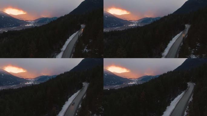 无人机: 汽车沿着高速公路行驶，穿过白雪皑皑的加拿大松树林。