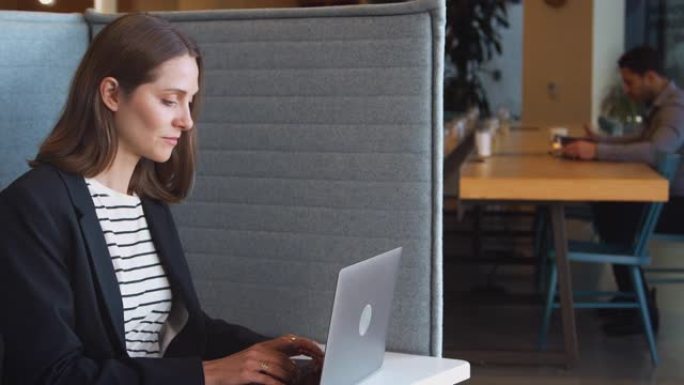 现代办公室工作空间隔间里的女商人使用笔记本电脑