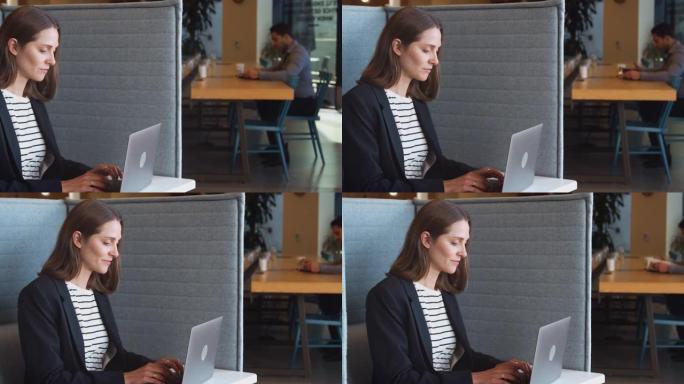 现代办公室工作空间隔间里的女商人使用笔记本电脑