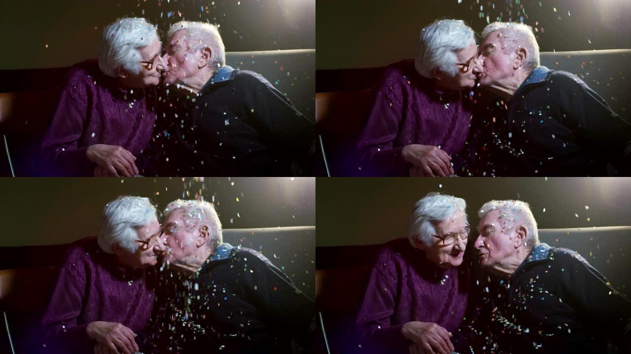 90岁生日时温柔的老夫妇玩五彩纸屑和慢动作接吻