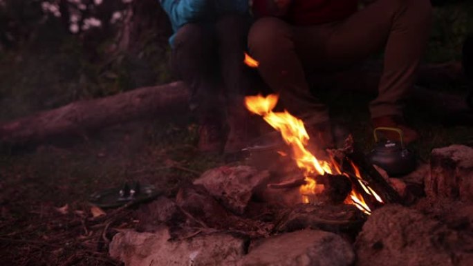一对夫妇坐在篝火旁准备饭菜的特写