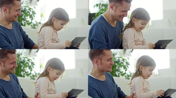 女孩在平板电脑上玩耍，坐在父亲的腿上