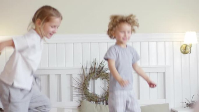 带着圣诞装饰品的舒适儿童房里的小孩在床上跳跃