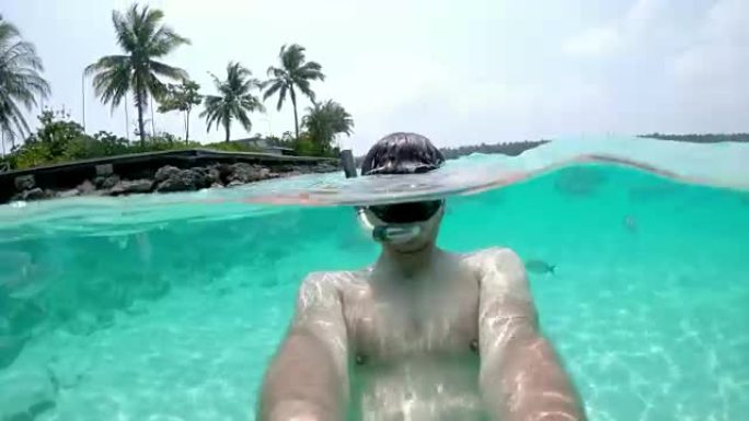 男子女士在马尔代夫热带海洋中使用可穿戴相机浮潜