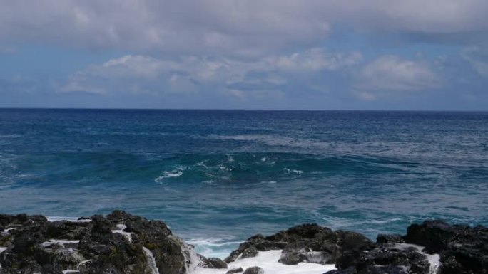 特写: 大浪逼近火山岛坠入多岩石的海岸。