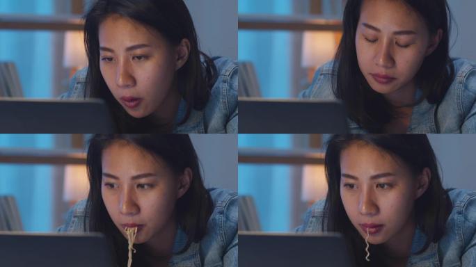 亚洲自由职业者聪明的商业女性吃方便面压力大，晚上在家客厅笔记本电脑工作时累了。