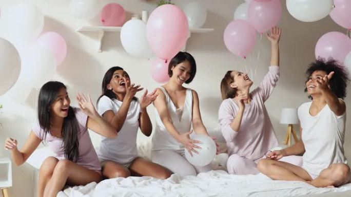 积极的多民族女孩玩气球庆祝睡衣派对