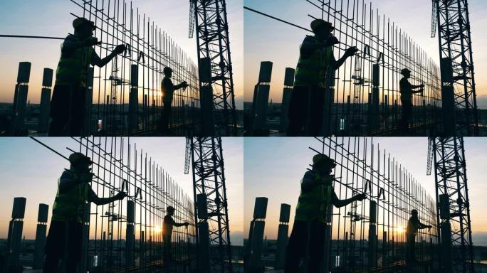 建筑工人正在日落时制作金属框架