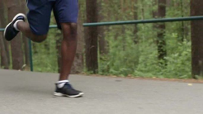 沿着森林路奔跑的黑人的腿