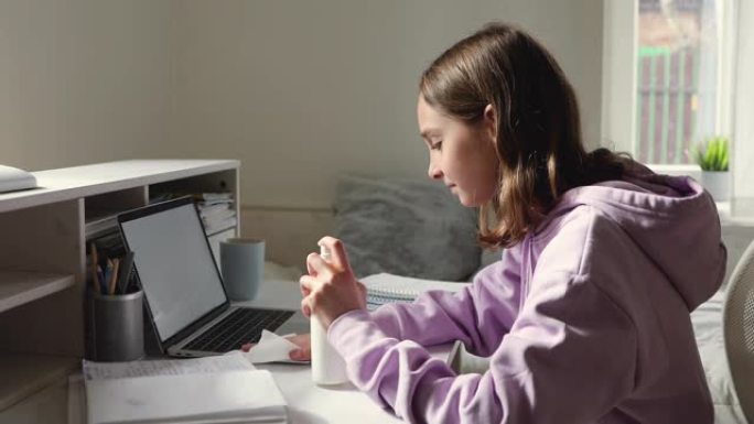 青少年女学生在家使用笔记本电脑喷洒消毒剂