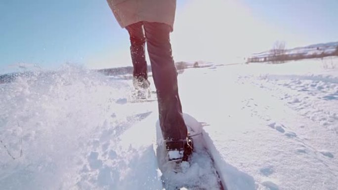 SLO MO女人雪鞋穿过雪地