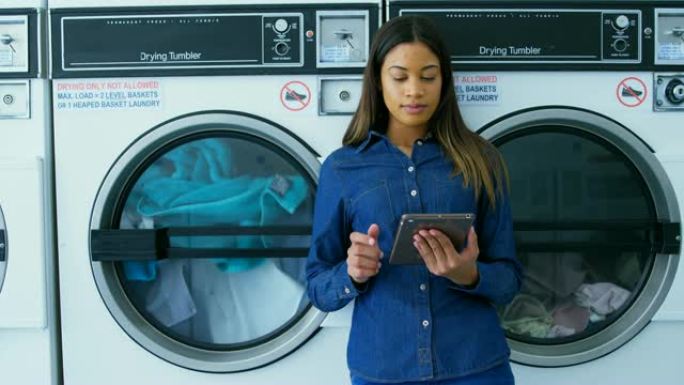 在4k自助洗衣店使用数字平板电脑的女人