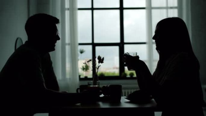 男人和女人在厨房桌子上碰杯喝酒的剪影