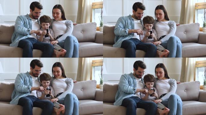 带着孩子儿子微笑的父母使用智能手机在沙发上放松