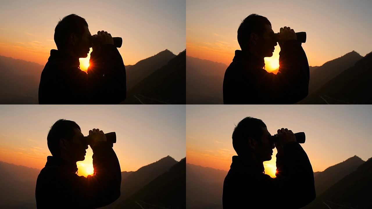 男子在山上用双筒望远镜向前看