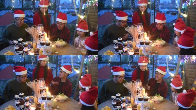 一个亚洲华人兄弟姐妹和朋友在房子的前院庆祝圣诞节晚餐，点燃蜡烛并摆放桌子