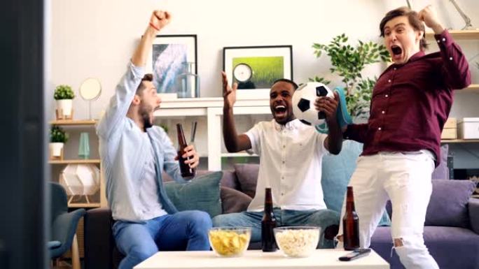 快乐的年轻人在电视上的足球比赛中庆祝进球