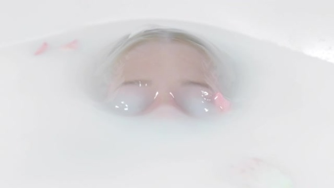 超级SLO MO女人浸泡在玫瑰花瓣的放松浴缸中