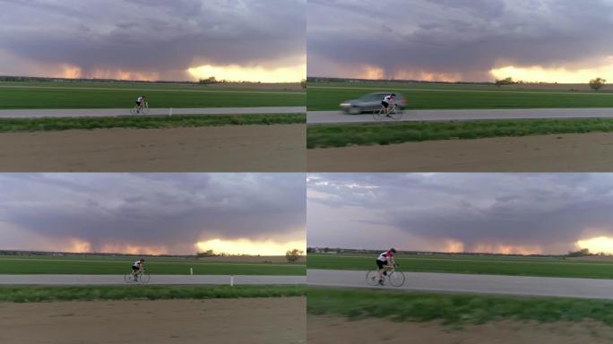 MS男骑车人在乡村道路上骑自行车，背景为暴风云