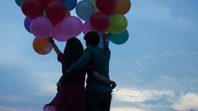 年轻夫妇拿着慢动作背景的气球。
