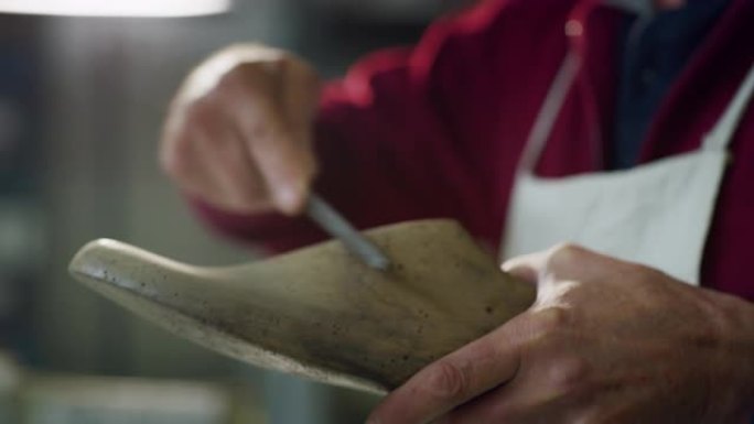 一个鞋匠在意大利鞋厂砍刀并准备工具的特写。