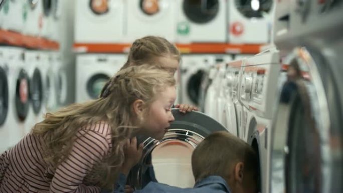 快乐的孩子在家电店和父亲一起检查洗衣机