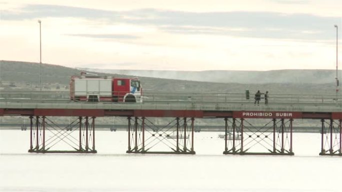 阿根廷马德林港一条长长的金属码头路上的消防车。