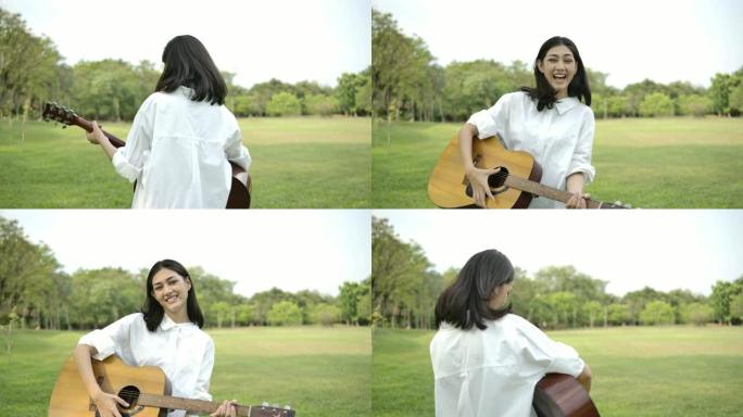 年轻迷人的亚洲女子在夏日公园弹吉他的肖像。具有幸福情感概念的女人。慢动作。