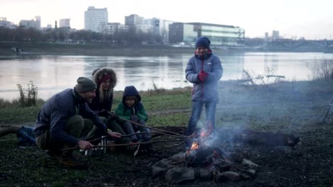 篝火里的家庭烤香肠。冬季乐趣。城市中的河边