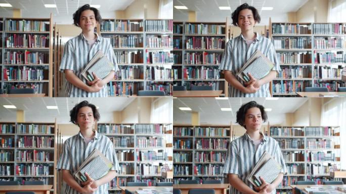 开朗的少年在大学图书馆里拿着书看着相机