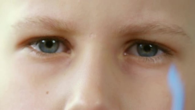 年轻的蓝眼睛男孩脱下眼镜