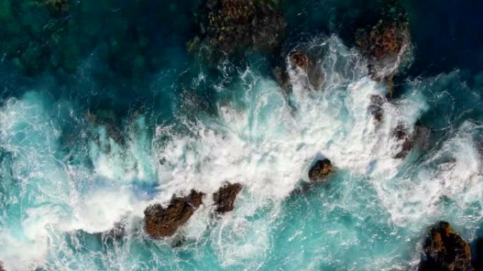 波浪在石头上破碎。海浪起泡和飞溅的海浪。空中俯视图。西班牙特内里费岛。4K, UHD