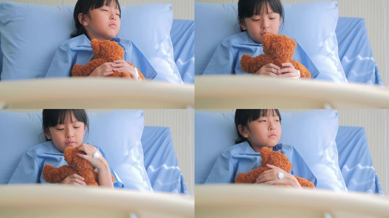 喜怒无常的女婴坐在医院的床上，独自看着泰迪熊。压力时刻