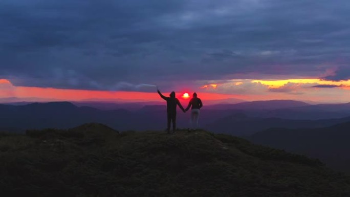 这对夫妇带着烟花棒站在一座美丽的日落山上