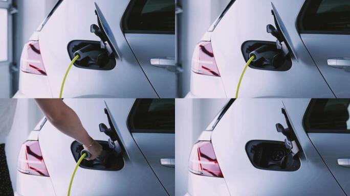 当女人从慢动作拍摄的车辆上取下充电电缆时，摄像机沿着车库中的电动汽车侧面跟踪