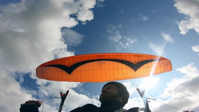 天空中的滑翔伞活动。男性滑翔伞正随着车辆逆天移动